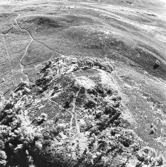 Oblique aerial view centred on the remains of the fort and possible cairn, taken from the NW.