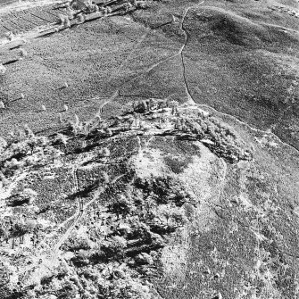 Oblique aerial view centred on the remains of the fort and possible cairn, taken from the W.