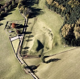 Oblique aerial view of Edzell, Castle Hillock centred on the remains of the motte-and-bailey castle with church and burial ground adjacent, taken from the E.