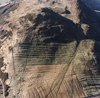 Oblique aerial view of Holyrood Park centred on the remains of cultivation terraces, a fort, rig and enclosures, taken from the ENE.