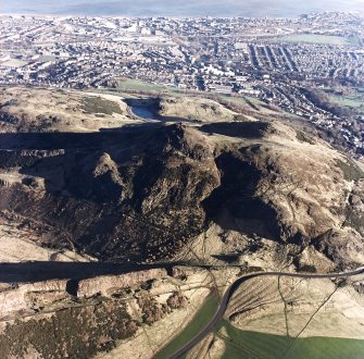 Oblique aerial view of Holyrood Park centred on Arthur's Seat with the remains of quarries on Salisbury Crags and cultivation remains in front, taken from the SW.