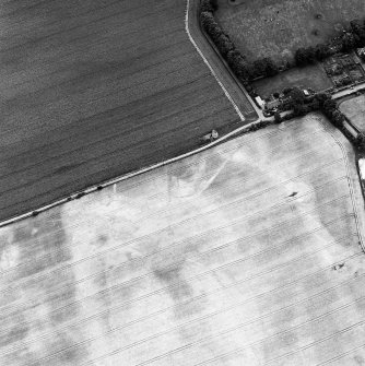 Phantassie, oblique aerial view, taken from the W, centred on the cropmarks of an enclosure and a possible building. A dovecot is visible in the centre of the photograph.