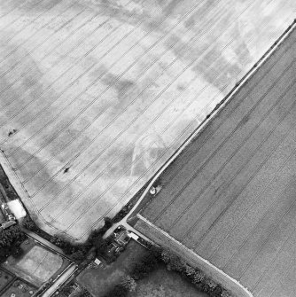 Phantassie, oblique aerial view, taken from the SE, centred on the cropmarks of an enclosure and a possible building. A dovecot is visible in the centre of the photograph.