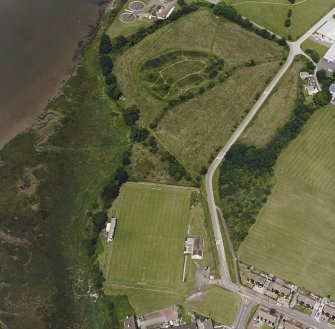 Oblique aerial view of Kirkcudbright Castle centred on earthworks with a football ground adjacent, taken from the SSE.
