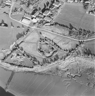 Oblique aerial view centred on the remains of the castle with Castle Mains house and school adjacent, taken from the W.