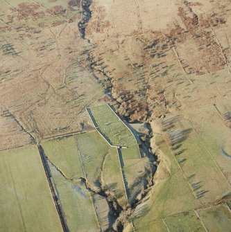 Oblique aerial view of Ettleton Sike centred on a burial-ground with the remains of a building, field-system, rig, sheepfold, hut and enclosure adjacent, taken from the SE.