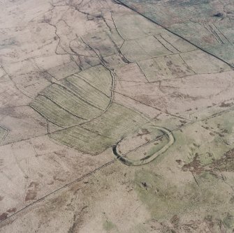 Oblique aerial view centred on the remains of the fort and palisaded enclosure with field-system, rig, boundary banks, enclosures and lazy beds adjacent, taken from the NW.