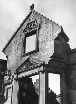 View of S crow-stepped gable with decorative carving above windows.