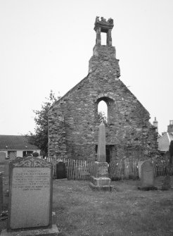 View from E showing the ruined gable, belfry and churchyard.