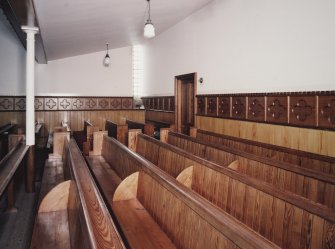 Interior. Pews and decorative timber lining. View from W