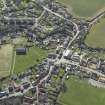 General oblique aerial view of the village, centred on the remains of the priory and the church, churchyard and manse, taken from the NNW.