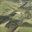 General oblique aerial view centred on the country house, garden, stable, footbridge and lake, taken from the SE.
