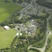 Oblique aerial view centred on the school, church, hospital and house, taken from the NW.