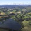 General oblique aerial view looking across the Loch of Clunie towards the Grampian Mountains with the remains of the possible crannog and the church and country house in the foreground, taken from the E.