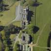 Oblique aerial view centred on the house with stable block and farm adjacent, taken from the S.