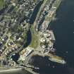 Oblique aerial view centred on the locks, canal basin, pier, harbour, lighthouse, church and buildings, taken from the S.
