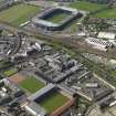 Oblique aerial view of Edinburgh centred on the Tynecastle Park football stadium with the North British Distillery adjacent and Murrayfield Stadium in the background, taken from the SE.