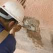 Mason applying mortar to castle prior to fitting new false spout