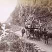 View of horse-drawn carriage with large group of people in the Pass of Melfort.
