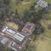Oblique aerial view centred on the country house with the stables and walled garden adjacent, taken from the NW.
