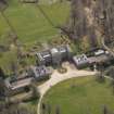 Oblique aerial view centred on the country house with the stable block adjacent, taken from the N.