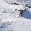 Oblique aerial view of fort, enclosure and settlements, buildings, enclosures and sheepfolds under snow, looking to W.