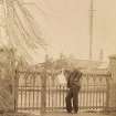 View of man at gate, possibly in Stanley.