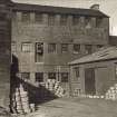 View of site from SW prior to taking down of 3 storey  building, formerly a Mauchline Box-making factory. The disused Rough Out Shed of the curling stone factory is on the left.