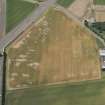 Oblique aerial view of East Fortune Airfield, First World War airship shed base under modern agricultural buildings, a military workshop building, and cropmark features relating to airship station, looking SW.