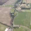 Oblique aerial view of a circular cropmark, part of the First World War airship station gas works, and East Fortune farm, looking ESE.