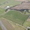 Oblique aerial view of a circular cropmark, part of the First World War airship station gas works, and East Fortune farm, looking NNW.
