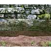 View of medieval graveslab set into wall of burial ground, NY 2577 8019.