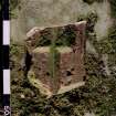 View of probable fragment of piscina in reuse as coping stone of wall of burial ground, NY 2576 8017.