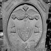 Gravestone dated 1831. Pair of rosettes, clasped hands, weaver's shuttle and reed; winged cherub, shield containing intials 'J Y'; spade, hourglass and turf-cutter.