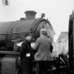 View showing men talking beside locomotive at Bogside Station