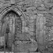 View of sculptured stones and arched doorway in railed enclosure.
Original negative captioned: 'Sculptured Stones and old Font. Church of Tullich near Ballater July 1902'.