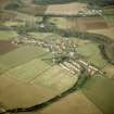 Oblique aerial view centred village with country house and walled garden adjacent, taken from the E.