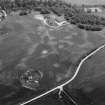 Oblique aerial view centred on the cropmarks of the timber hall, ring ditch, enclosures and pits at Mondobbo House, looking to the SE.