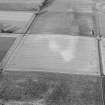Oblique aerial view centred on the cropmarks of a possible palisaded enclosure, field system, ring-ditches, pits and rig at Suttie and Wester Fintray, looking to the ENE.