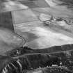 Oblique aerial view centred on the cropmarks of the unenclosed settlement, field system and rig at Braehead with the farmstead adjacent, looking to the SSW.