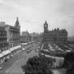 General view of Princes Street from Scott Monument to the east showing the North British Hotel, Waverley Gardens, Calton Hill and a busy street with pedestrians, trams and cars.