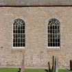 View of two large arched windows and blocked doorway and window in South wall of church.