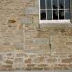 Detail of blocked window at ground level in S wall of church.