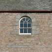 Detail of small arched window at roof level in S wall of church.