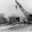 View from SE of standard gauge locomotive shed with two diesel electric locomotives and a railway crane outside Bishopton Royal Ordnance Factory.
