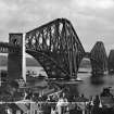 View of the bridge in use seen from North Queensferry. 
Titled. 'The Forth Bridge. Length including Viaduct 8098 Ft. Height 369 Ft. Spans 1710 Ft each.  917.'