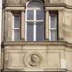 View of carved portrait head, in medallion above third floor window on W bay of Princes Street facade.