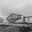 View of the Forth Bridge under construction seen from the South from the slipway.
