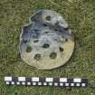 Perforated lead disc, probably part of a pump filter from the wreck-site. Scale in inches and centimetres.
