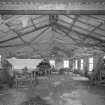 Interior view of part of the mess hall complex showing steel 'A' frame roof trusses and the remains of the asbestos ceiling insulation.